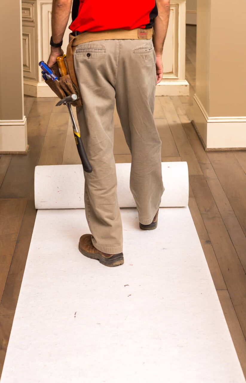 Worker laying SurfaceGuard Pro™ floor protection, ensuring exceptional work without a damaged floor.