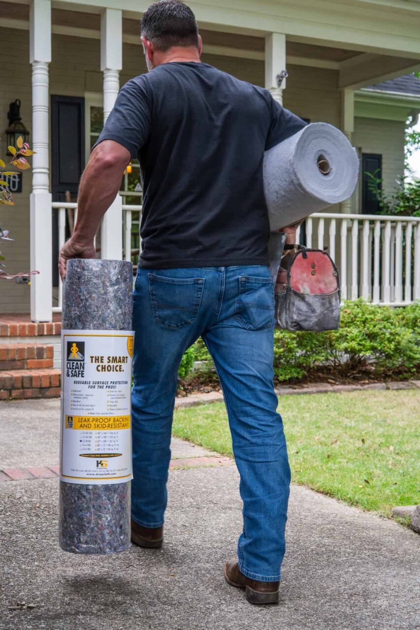 Man carrying rolls of SurfaceGuard Pro™ material, symbolizing our story of exceptional work and protecting your reputation.