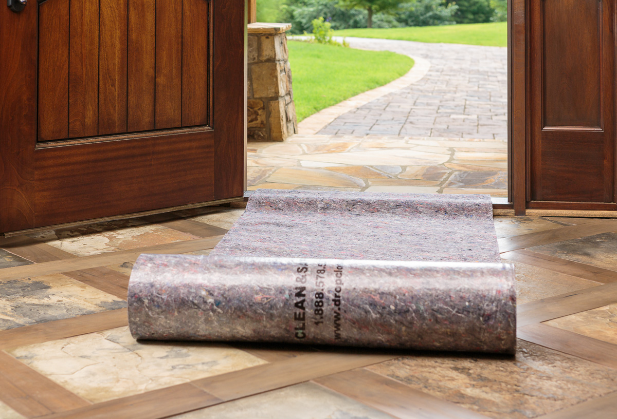 Protect job site surfaces from winter with a rolled-out temporary floor covering at an open wooden door entryway.